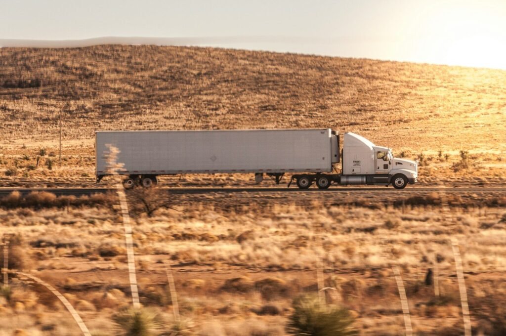 a white semi truck driving down a rural road